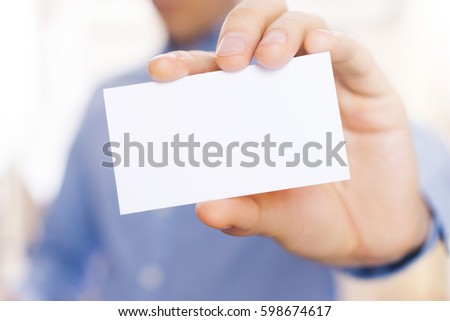 Blank business card in person hand. Horizontal shot. Close-up