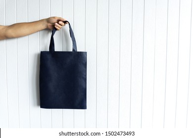 Blank Canvas Dark Blue Tote Bag, Design Mockup With Mans Hand On White Background. No Plastic Concept