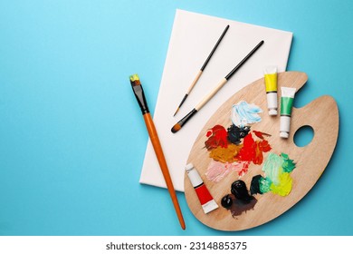 Blank canvas, tubes of oil paints, brushes and palette on light blue background, top view. Space for text - Powered by Shutterstock