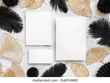 Blank Cards On Marble Table Near Black Feathers And Golden Leaves Top View. Wedding Set Mockup. Elegant Femminine Suite With Paper Cards, Flat Lay 