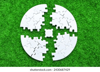 Blank circular puzzle split into four sectors arranged around the center piece on a lush green meadow. Nature, harmony and balance related concept.