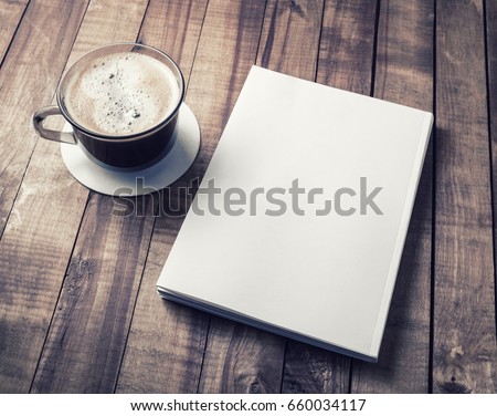 Blank closed book and coffee cup on vintage wooden background. Responsive design template.