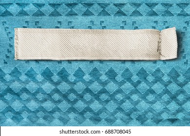 Blank Clothes Label On Blue Textile Background Closeup