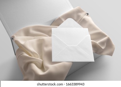 Blank Clothing Box, Package With Elegant Silk Fabric And Blank Envelope With Greetings Card Mockup To Place Your Design, On A White Background. Isometric View Fashion Branding Scene