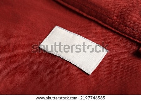Blank clothing label on red shirt, closeup