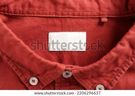 Blank clothing label on red shirt, top view