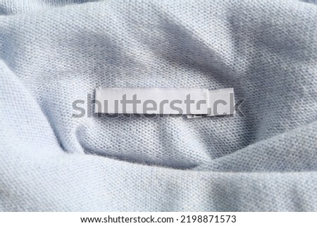 Blank clothing label on stylish cashmere apparel, closeup