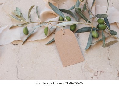 Blank Craft Paper Gift Tag, Label Mockups With Olive Leaves And Branches. Silk Ribbon, Marble Backgound. Modern Template For Branding Identity. Summer Sale, Birthday Or Wedding Concept. Top View. 