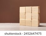 Blank cubes on wooden table against brown background, space for text