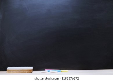 Blank Dark blackboard with color Chalk and eraser on the frame for drawing in Classroom. Horizontal composition. copy space empty Chalkboard Background. back to school.
