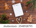 Blank Dear Santa letter with Christmas decor. A blank "Dear Santa" letter on a wooden table surrounded by gingerbread cookies, candy canes, pinecones, and festive decorations.