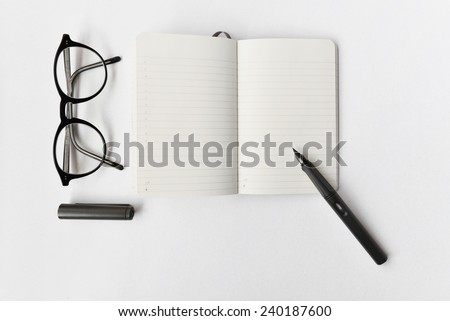 Blank diary, pen, and glasses on white background