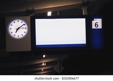 Blank digital display board at train station with clock, empty screen mockup for timetable or advertisement