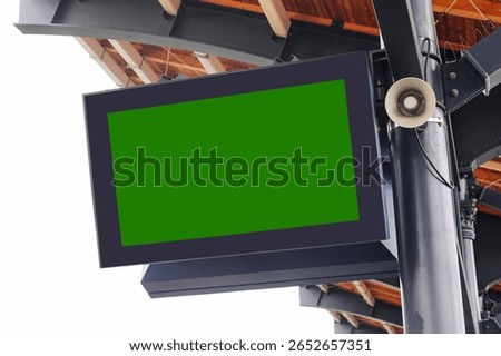 Blank digital screen on train station. Green chroma key background for message or timetable. Display under roof with speaker. Public transport infrastructure. Mockup for travel information display.