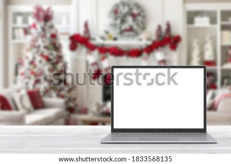 Blank display screen laptop computer on white wood table. Modern cozy comfortable home living room with Christmas decor. Home office desk workspace. Mock up copy space. Winter sales, online shopping