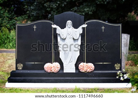 Blank elaborate gravestones with jesus figure in between and flowers at base. Beautiful marble double headstones.