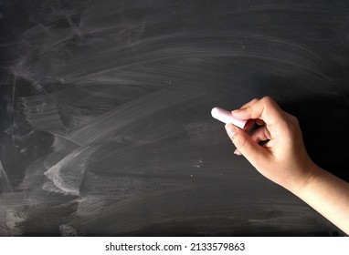 Blank empty blackboard chalkboard texture banner wallpaper surface background.Hand writing on black chalk board holding chalk,traces.Texture backdrop for text.School,Education,Cafe,bakery,restaurant.