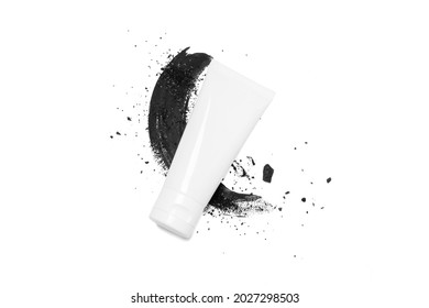 Blank or empty cosmetic plastic tube with charcoal with charcoal powder background. Skin care,Health care,body wash gel beauty concept.Isolate on White background. top above view.