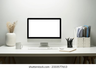Blank empty desktop computer, potted plant and books on white table. White screen for your advertising text message 