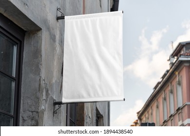 Blank Flag Sign Mockup In The Urban Environment, On The Facade, Empty Space To Display Your Store Sign Or Logo