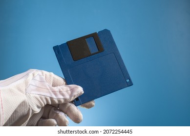 Blank Floppy Disc Of Blue Color In Hand, On A Blue Background. Outdated Retro Digital Media. Old Computer Technology.