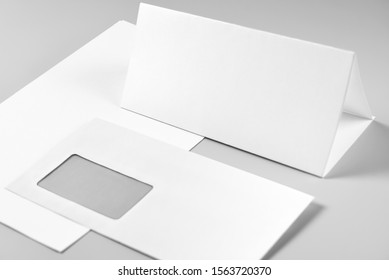 Blank Folded Sheet of Paper, Letterhead, or Flyer and Envelope over Stack of Paper