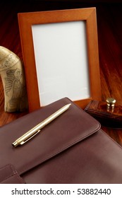 Blank Frame, Leather Case, Gold Pen, Scrimshaw Whale's Tooth And Blotter Shot On Rosewood Wooden Desk