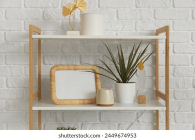 Blank frame with plant on shelf near white brick wall