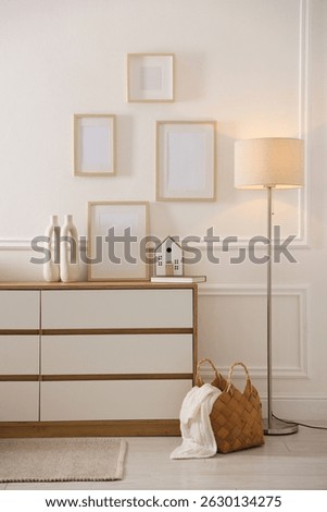 Blank frames on wall and chest of drawers indoors