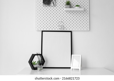 Blank frames, reed diffuser and planter on table near light wall