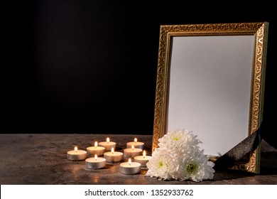 Blank Funeral Frame, Candles And Flowers On Table Against Black Background