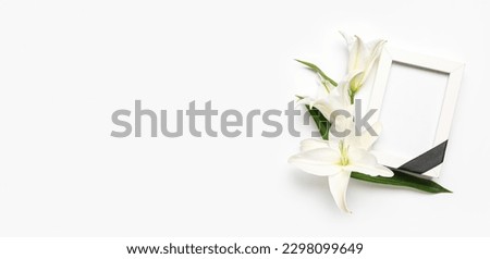 Blank funeral frame and lily flowers on white background with space for text