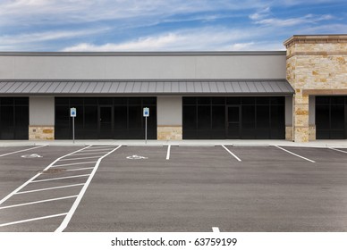 A blank, generic strip mall against a blue sky with an empty parking lot.
