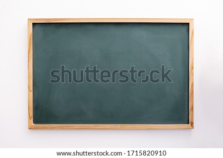 blank green chalkboard on a white wall, school and teaching concept, copy space for text