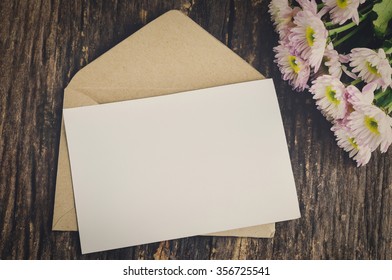 Blank greeting card with brown envelope and white Mum flower on wooden table with vintage and vignette tone - Powered by Shutterstock