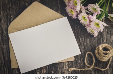 Blank greeting card with brown envelope and white Mum flower on wooden table with vintage and vignette tone - Powered by Shutterstock