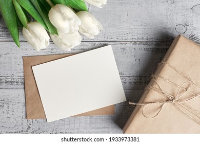 Blank Greeting Card With Gift Box, Tulip Flowers Bouquet And Copy Space On Wooden Background