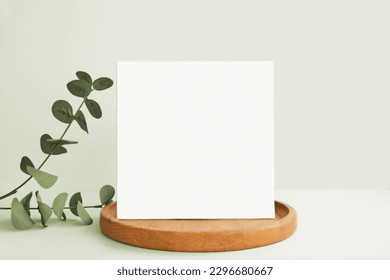Blank Greeting Card, Invitation Mockup. Front view Eucalyptus Plant, Modern Wooden Plate, Boho Paper Mock Up on Green Table Copy Space. Minimal Business Brand Template. Soft Shadow Nordic Flier Design - Shutterstock ID 2296680667
