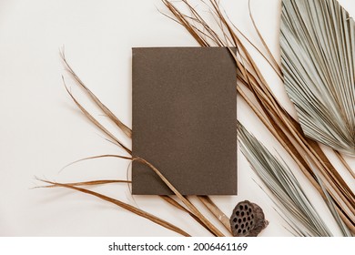 Blank greeting card mockup, dry palm leaf  on beige table backgound. minimal branding, template for wedding in Scandinavian style. Still life mock up