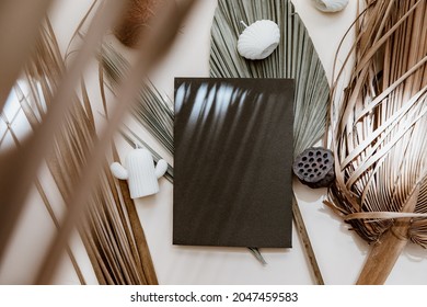 Blauer Grußkartenmock, trockenes Palmenblatt und Kerzen auf beigem Tischhintergrund. minimales Branding, Vorlage für Hochzeit im skandinavischen Stil. 