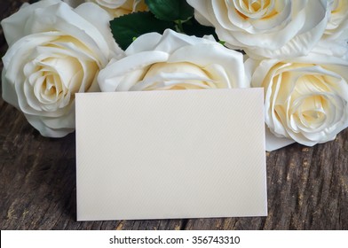 Blank Greeting Card And White Artificial Rose On Old Wooden Table With Vintage And Vignette Tone