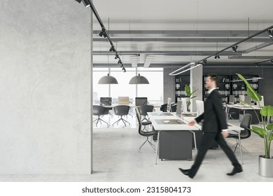 Blank grey concrete wall with empty space for poster or image frame in a corridor of modern loft office interior and walking person, mockup
