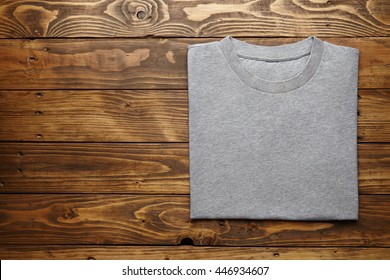 Blank grey t-shirt accurately folded on rustic wooden table top view mockup - Powered by Shutterstock