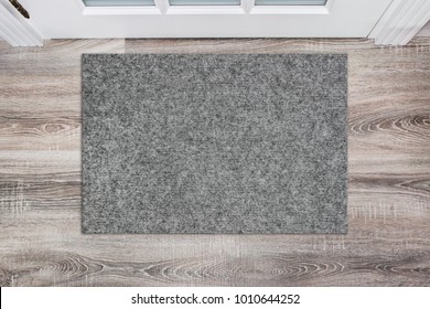 Blank grey woolen doormat before the white door in the hall. Mat on wooden floor, product Mockup
