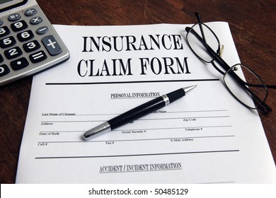 Blank Insurance Claim Form And Pen On Desktop With Calculator (Form Was Created For This Shooting - No Property Release Necessary)