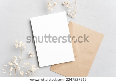 Blank invitation or greeting card mockup with flowers and envelope, wedding card flat lay