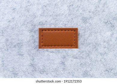 Blank label made of brown genuine leather tag sewn on to light gray felt material. Copy cpase, blank.
