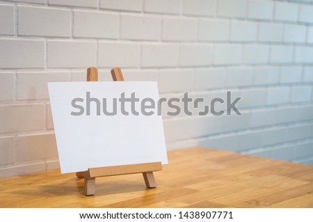Blank label paper on the wood photo Stand, wood photo holder, white blank paper on frame. mockup. mini sign on wooden table. Layout for menu, sign, label, text. Mini white board. Welcome. Copy Space.