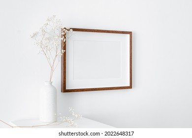 Blank Landscape Frame Mockup On White Wall With Furniture And Dry Gypsophila Plant Decorations. Minimalistic Interior With Artwork Mockup.