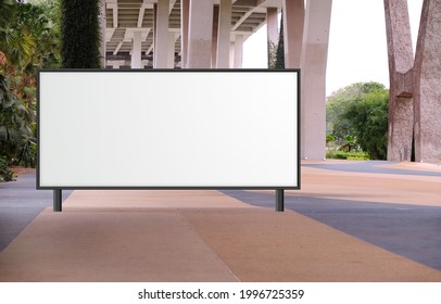 Blank Large Billboard Advertising Banner Mockup In A Large Open Space With Plants Under A Modern Bridge. Large Horizontal Digital Display Screen, An Out-of-home OOH Media Display Space
